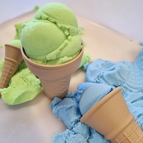 PLA ijsjes set Plastic ijshoornvormen gevuld met groene en blauwe sensorische speelzand of magic sand, liggend op een wit oppervlak – het lijkt op echt ijs, perfect voor fantasiespel en ontwikkeling van fijne motoriek bij kinderen.