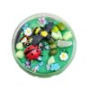 Rond doosje gevuld met groene sensorische klei, versierd met een plastic lieveheersbeestje, bij, kleurrijke steentjes, bloemetjes en kleine vlinders – een vrolijke lentetuin in miniatuurformaat.t5