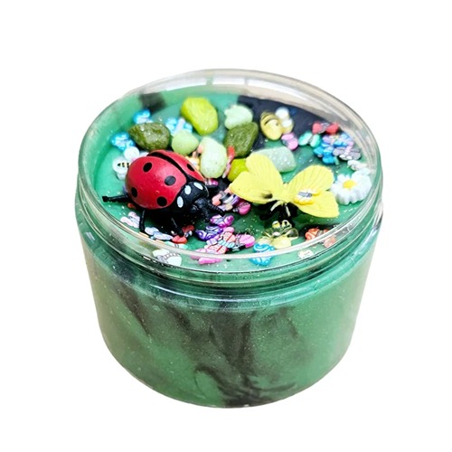 insekten speelklei2 Rond afsluitbaar doosje gevuld met groene sensorische klei, versierd met een plastic lieveheersbeestje, bij, kleurrijke steentjes, bloemetjes en kleine vlinders – een vrolijke lentetuin in miniatuurformaat.
