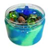 Rond doosje gevuld met groene en blauwe sensorische klei, versierd met een plastic libelle, bever, kikker en kleurrijke steentjes, boomstam en glitte – een zoemende sloot- of rivierzijde in miniatuurformaat.