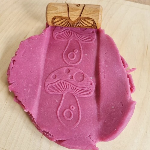 rollerpaddestoel1 Houten sensorische roller met rose klei van het merk Kiddi met ingegraveerd paddenstoelenpatroon – ideaal voor sensorisch spel met klei of speelzand.