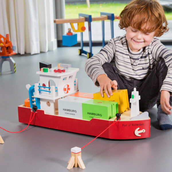 kind-speelt-met-houten-containerboot-rollenspel Kind speelt met houten containerboot en meerpalen